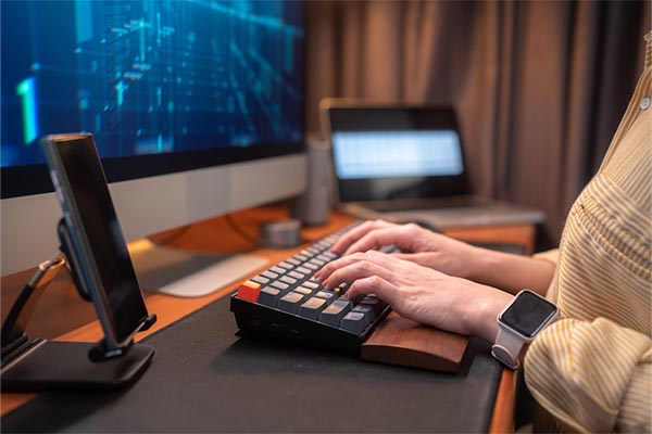 pessoa digitando no seu teclado com apoio de pulso na base do teclado indicando a sua preocupação com ergonomia
