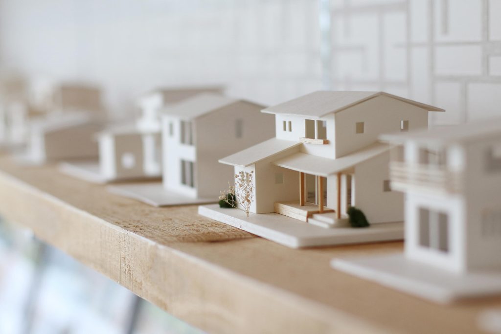 Modelos em miniatura de casas sobre prateleira, ilustrando o planejamento e a valorização imobiliária.